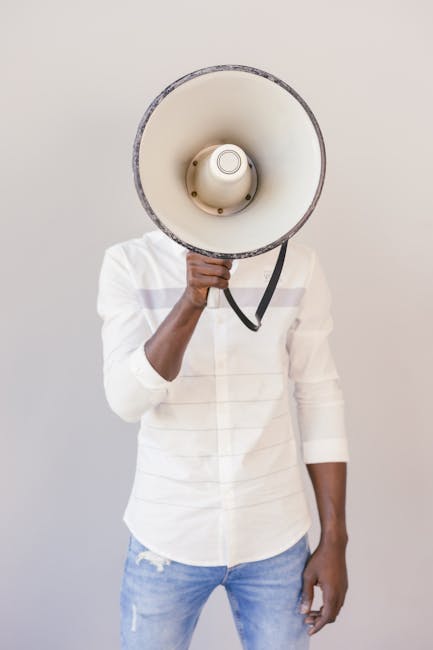 Creative studio shot of a person holding a megaphone over their face, expressing anonymity or communication themes.